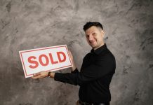 man holding "sold" sign