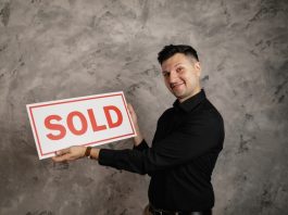 man holding "sold" sign